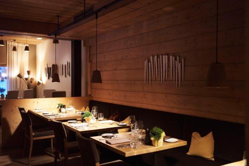 a restaurant with wooden walls and tables and chairs at Holzhotel Forsthofalm in Leogang