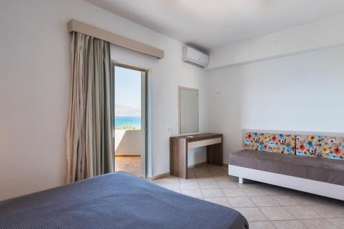 a bedroom with a bed and a desk and a window at Wink Bnb Paraliaki in Kissamos