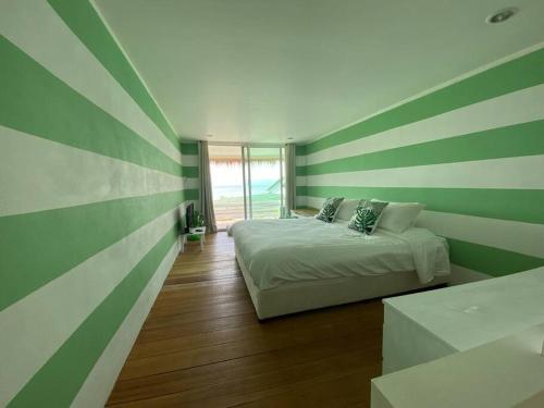 a bedroom with a bed with green and white stripes at Beach house in Baan Tai
