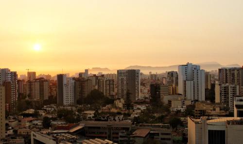 a city skyline with the sun setting behind buildings at Apartamento dúplex exclusivo y céntrico in Lima