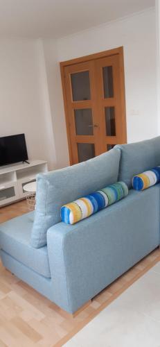 un sofá azul con almohadas en la sala de estar en Apartamento Alfa, en Monforte de Lemos
