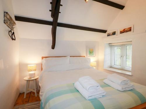 een slaapkamer met een groot bed en handdoeken bij Ivy Cottage in Tintagel