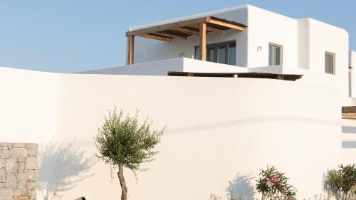 a white house with a tree in front of it at Alio Naxos Luxury Suites in Agios Georgios