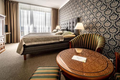 ブルノにあるHotel Fontánaのベッド、テーブル、椅子が備わるホテルルームです。
