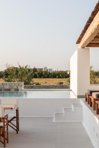 a white house with a pool and tables and chairs at Alio Naxos Luxury Suites in Agios Georgios