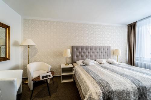 a bedroom with a bed and a chair and a window at Hotel Fontána in Brno