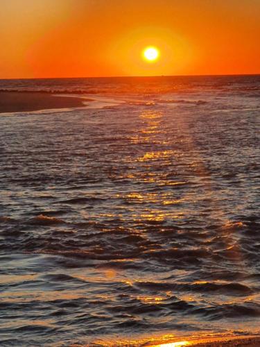 a sunset over the ocean with a beach at Appartement, Les TEMPLIERS, RDC VUE MER PROCHE CENTRE VILLE in Houlgate