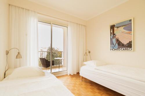 deux lits dans une chambre blanche avec une fenêtre dans l'établissement EXCEPTIONNEL 4 pieces vue panoramique baie des anges proche plage, à Nice