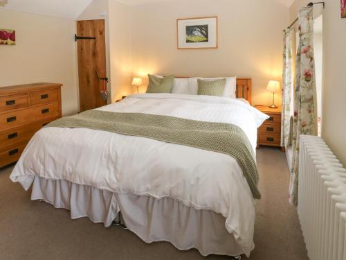 a bedroom with a large white bed and two lamps at Buttercup Cottage in Bakewell