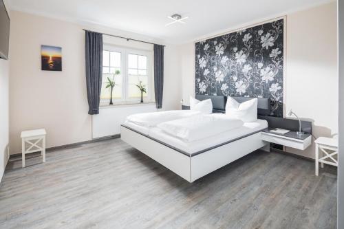 1 dormitorio con 1 cama blanca grande y papel pintado en blanco y negro en Albatros en Norderney