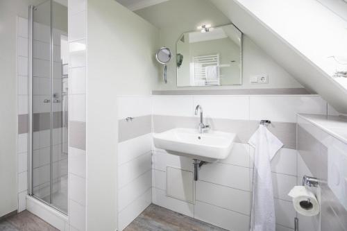 Baño blanco con lavabo y espejo en Albatros en Norderney