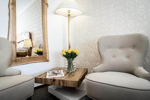 a living room with a chair and a table and a mirror at Hotel Fontána in Brno