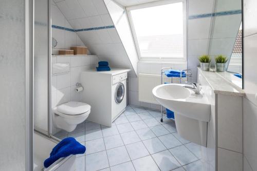 een badkamer met een wastafel en een wasmachine bij FeWo am Park in Norderney
