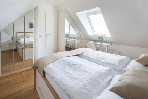 een witte slaapkamer met een bed en een raam bij FeWo am Park in Norderney