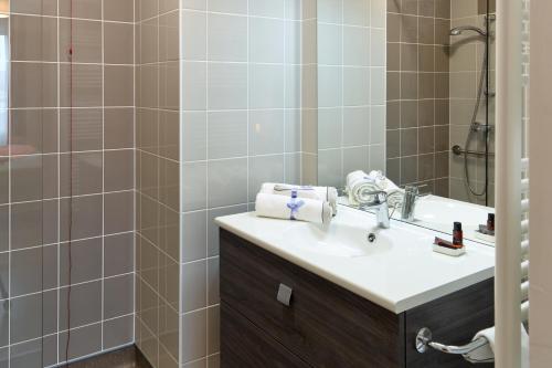 La salle de bains est pourvue d'un lavabo et d'une douche. dans l'établissement Zenao Appart'hôtels Montreuil, à Montreuil