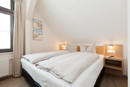 een slaapkamer met een groot wit bed en een raam bij Jann 66 in Norderney