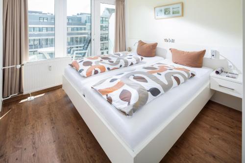 Cette chambre comprend un lit blanc et une grande fenêtre. dans l'établissement Kaiserhof 10, à Norderney