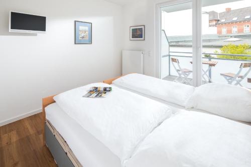 a bedroom with two beds and a balcony at John Silver in Norderney