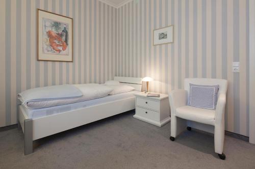 1 dormitorio con 1 cama y 1 silla blanca en Lenz, en Norderney
