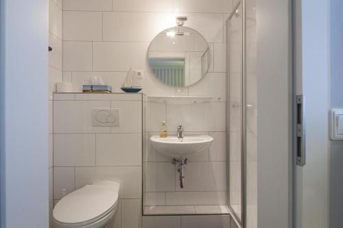 Un baño con inodoro, lavabo y espejo. en Lenz, en Norderney