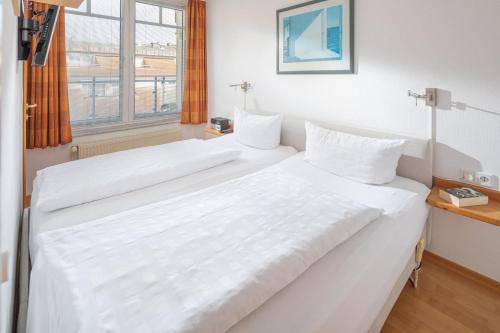 a large white bed in a room with a window at Kleine Möwe 11 in Norderney