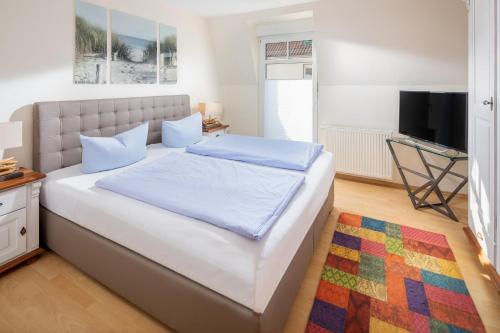 ein Schlafzimmer mit einem großen weißen Bett und einem Fernseher in der Unterkunft Haus Friederike in Norderney