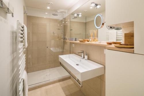 een witte badkamer met een wastafel en een douche bij Neys Beach Loft in Norderney