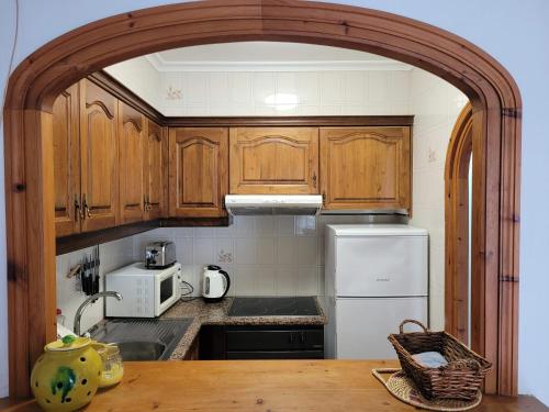 a kitchen with wooden cabinets and a white refrigerator at Apartamento Gecko in Son Parc