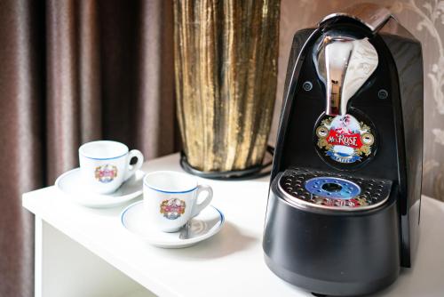 a black coffee maker sitting on a table with two cups at Hotel Fontána in Brno