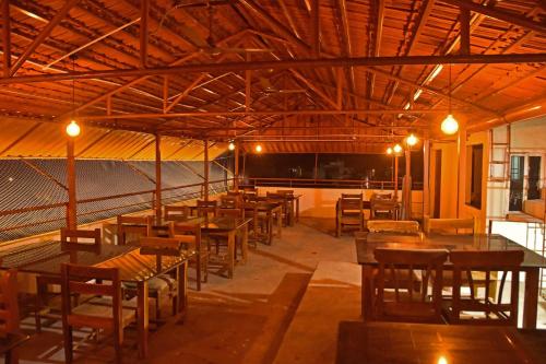 un restaurante con mesas de madera, sillas y luces en Ruthran Guest House, en Mahabalipuram