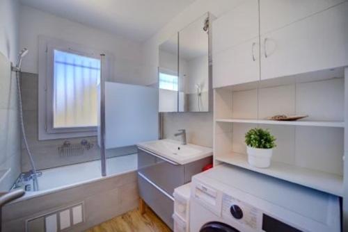 un bagno bianco con lavandino, vasca e lavandino di Très bel appartement Climatisé Terrasse et Vue Mer a Bandol