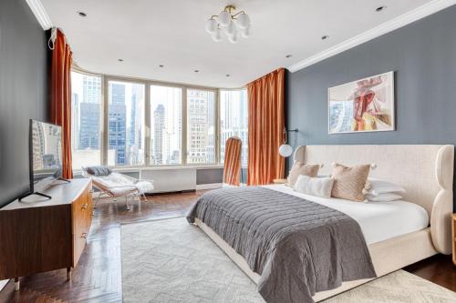 - une chambre avec un lit, une télévision et quelques fenêtres dans l'établissement Midtown East 5br w balconies nr Central Park NYC-1086, à New York