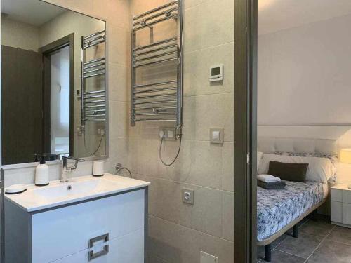 een badkamer met een wastafel, een spiegel en een bed bij Apartamento de lujo en primera linea de playa in Benidorm