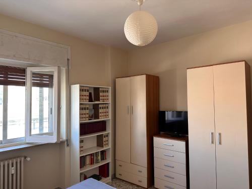 a bedroom with white cabinets and a television and a window at house green station in Bari