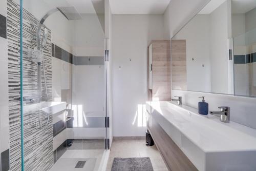 een witte badkamer met een wastafel en een douche bij La Maison ORE - Avec jardin in Bordeaux