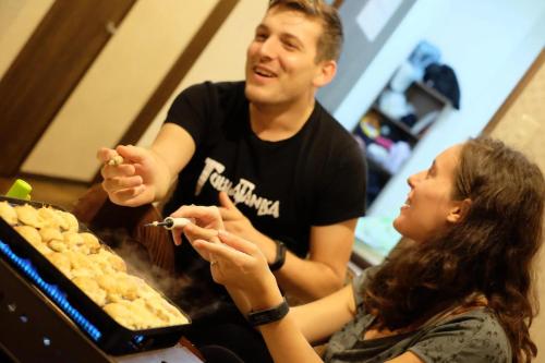 a man and a woman sitting next to a table with food at Osaka Namba Hostel MIYABI in Osaka