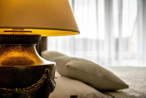 a lamp sitting next to a couch with a pillow at Hotel Fontána in Brno