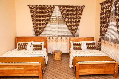a bedroom with two beds and a window with curtains at Materuni Homes in Moshi
