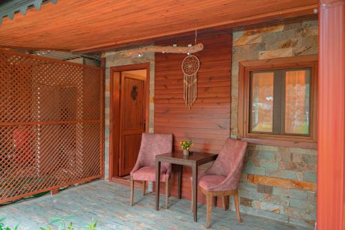 a porch with two chairs and a table and a window at Keyif Pension & Aparts in Cıralı