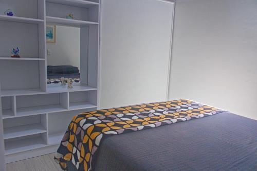 um quarto com uma cama e prateleiras em Villa Namaste, Cabaña Namaste 1 em Curití