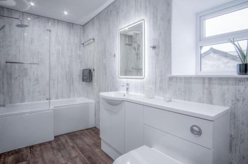 a white bathroom with a tub and a toilet and a sink at The Barn At Kiln Park - 2 Bed Cottage - Narberth in Narberth