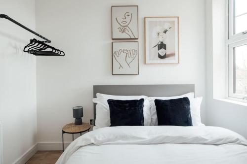 Dormitorio blanco con cama con almohadas blancas y negras en Modern 2 Bedroom Flat in Ilford, London en Ilford