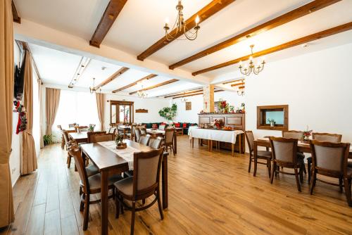 ラキツェレにあるPensiunea Popas in Apuseniのテーブルと椅子が備わるウッドフロアのレストランを併設しています。