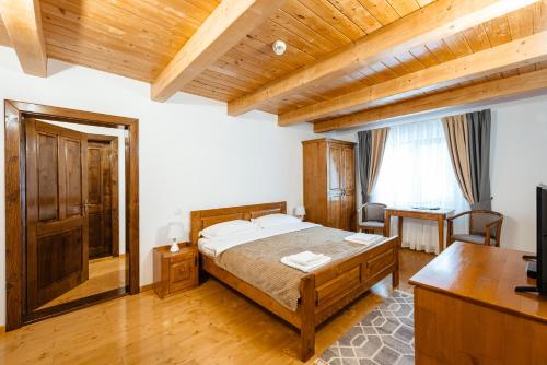 a bedroom with a large bed and a desk and a desk at Pensiunea Popas in Apuseni in Răchiţele