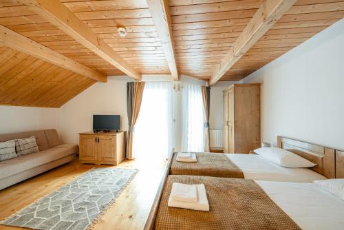 a large room with two beds and a couch at Pensiunea Popas in Apuseni in Răchiţele