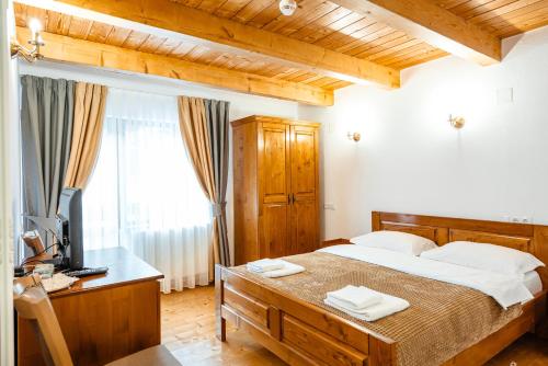 a bedroom with a bed and a desk with a television at Pensiunea Popas in Apuseni in Răchiţele