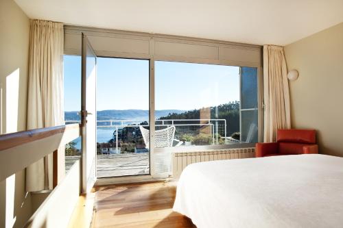 um quarto com uma cama e uma grande janela em Hotel A Miranda em Feás