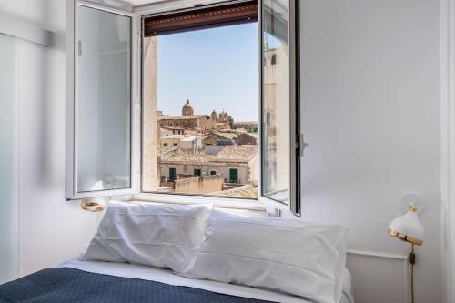 Schlafzimmer mit einem Fenster mit Stadtblick in der Unterkunft Mansarda Aurispa in Noto
