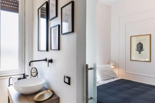 a bathroom with a white sink and a bed at Mansarda Aurispa in Noto