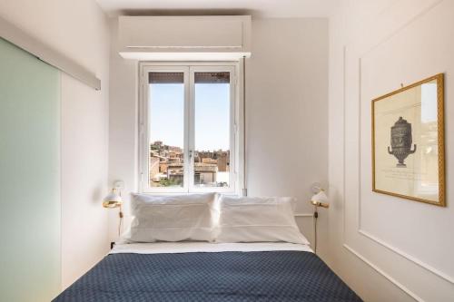 a white bedroom with a bed and a window at Mansarda Aurispa in Noto
